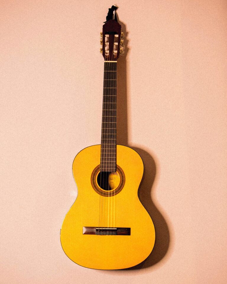 Home Yellow acoustic guitar hanging on a wall, showcasing its design and craftsmanship.