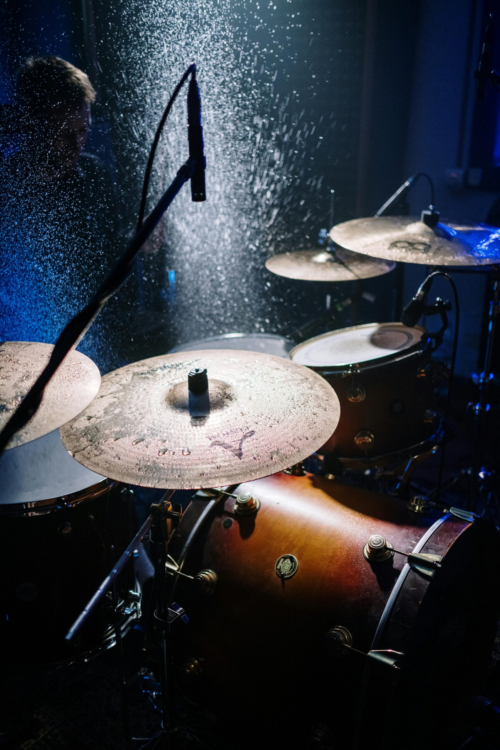 Vibrant image of a drum set with water splashing on cymbals under dramatic lighting.